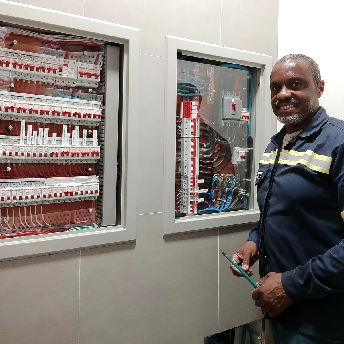 Ronaldo Américo, de uniforme, ao lado de quadros elétricos de distribuição